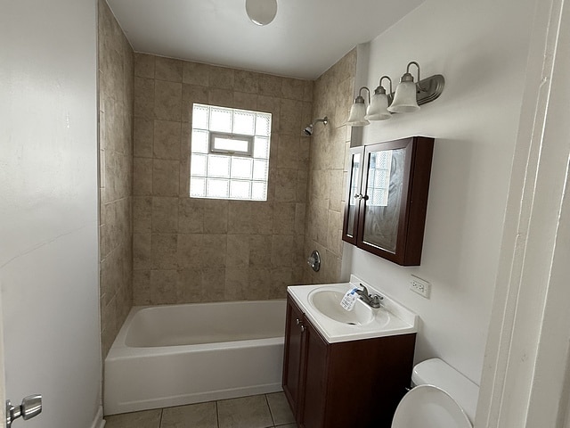 full bathroom with toilet, tile patterned flooring, vanity, and tiled shower / bath