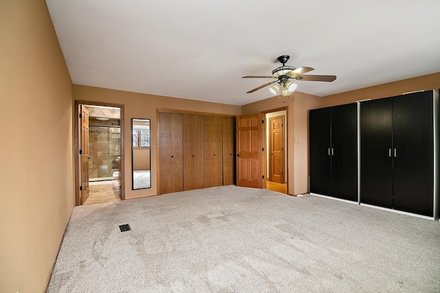 unfurnished bedroom featuring light carpet, ceiling fan, ensuite bath, and visible vents