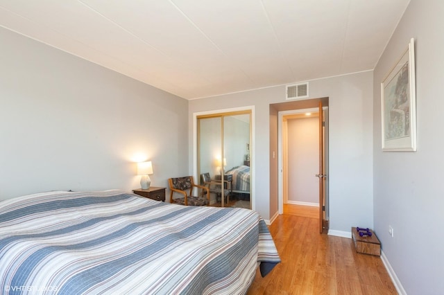 bedroom featuring a closet, baseboards, visible vents, and light wood finished floors