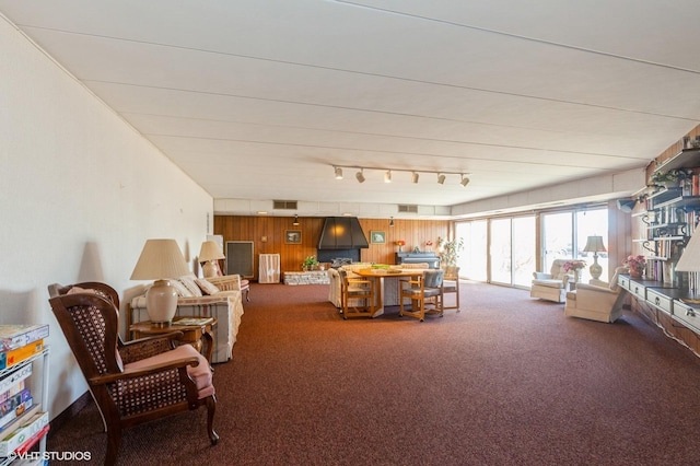 carpeted living room featuring visible vents and wooden walls