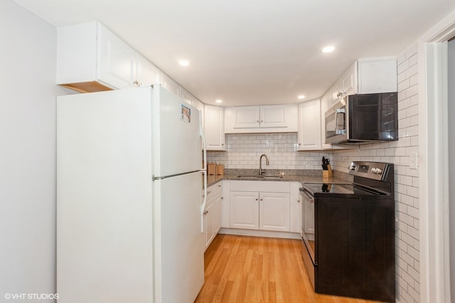 kitchen with freestanding refrigerator, a sink, decorative backsplash, black range with electric cooktop, and stainless steel microwave