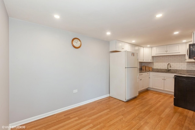 kitchen featuring tasteful backsplash, white cabinetry, freestanding refrigerator, and light wood-style floors