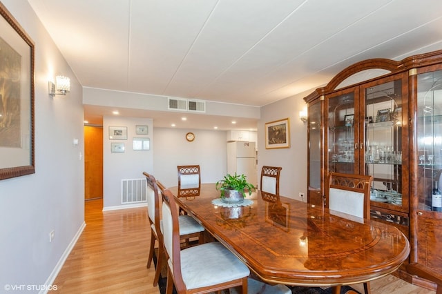 dining room with light wood finished floors, visible vents, and baseboards