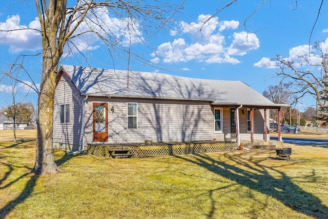 view of front of home with roof with shingles, a porch, and a front yard