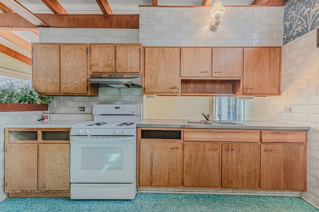 kitchen featuring under cabinet range hood, a sink, light countertops, decorative backsplash, and white gas range