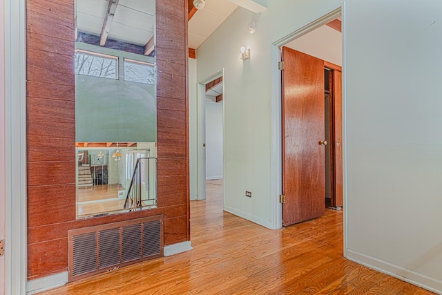 corridor featuring visible vents, beamed ceiling, baseboards, and wood finished floors