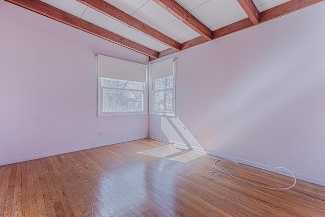 spare room with wood-type flooring, beam ceiling, and baseboards