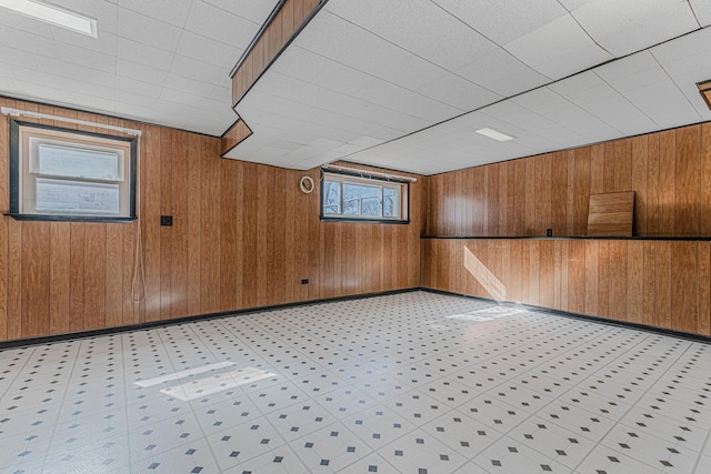 below grade area featuring baseboards, light floors, and wooden walls