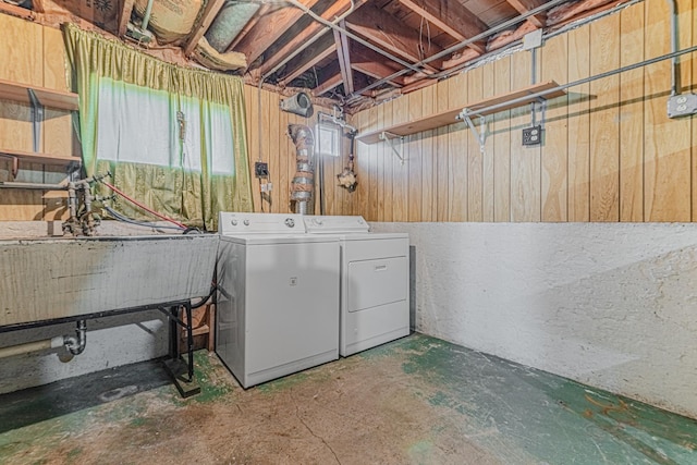 washroom featuring laundry area, independent washer and dryer, wooden walls, and a sink