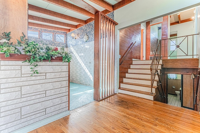 stairway with beam ceiling and wood finished floors