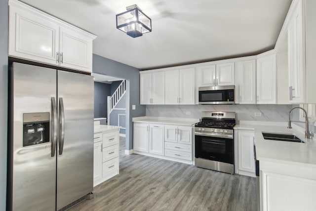 kitchen featuring sink, white cabinetry, light hardwood / wood-style floors, stainless steel appliances, and decorative backsplash