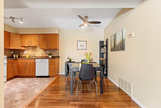 kitchen featuring brown cabinetry, white appliances, visible vents, and decorative backsplash