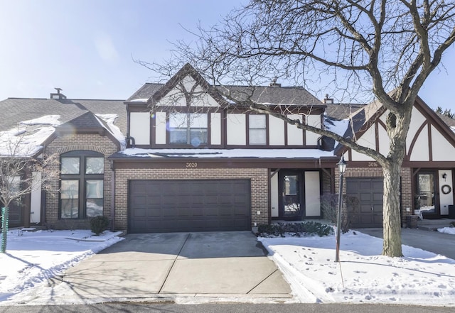 english style home featuring a garage, brick siding, and driveway