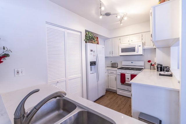 kitchen with white appliances, light wood finished floors, white cabinets, light countertops, and a sink