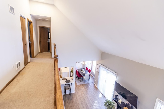 hall featuring baseboards, an upstairs landing, visible vents, and light wood-style floors