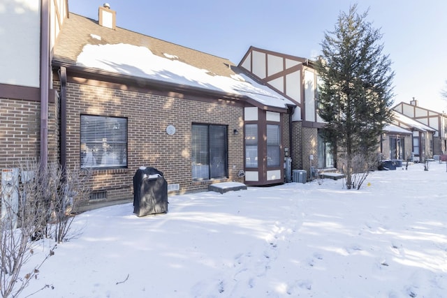 snow covered rear of property with french doors, brick siding, crawl space, and cooling unit