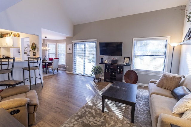 living room featuring high vaulted ceiling, dark wood-style flooring, a notable chandelier, and baseboards