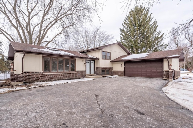 split level home with brick siding, driveway, and an attached garage