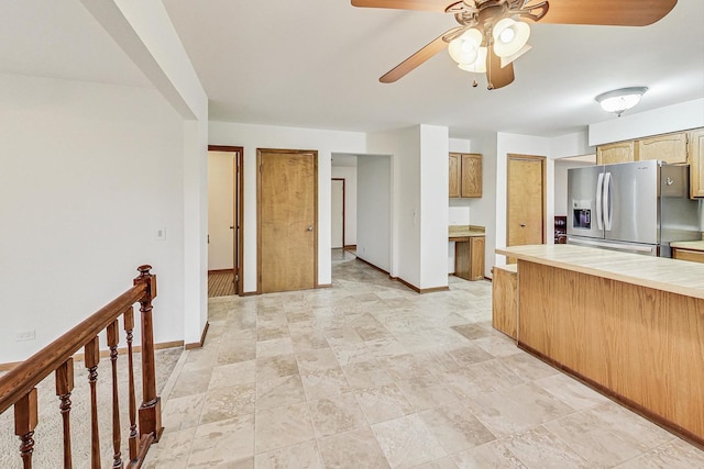 kitchen featuring a ceiling fan, baseboards, light countertops, and stainless steel fridge with ice dispenser