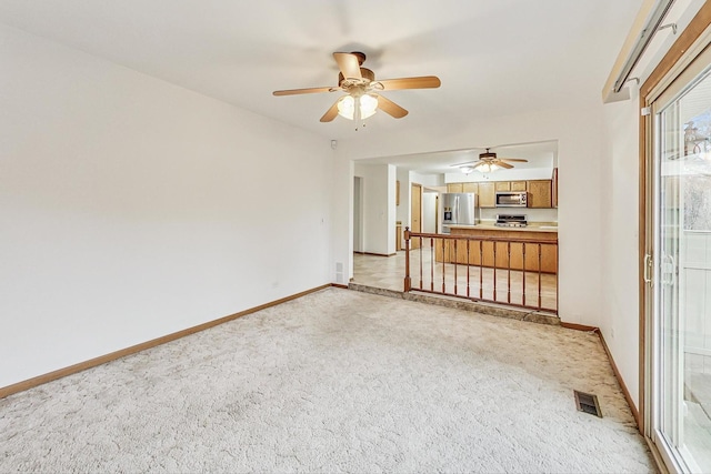 unfurnished room with light carpet, ceiling fan, visible vents, and baseboards