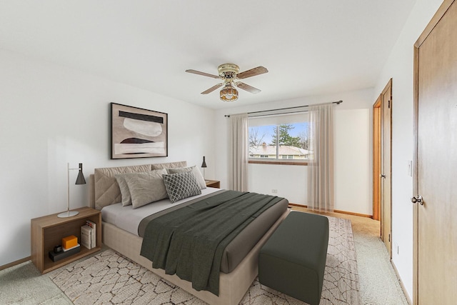 bedroom with a ceiling fan, light carpet, and baseboards