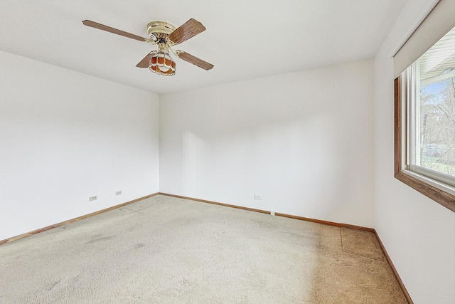 carpeted empty room with a ceiling fan and baseboards