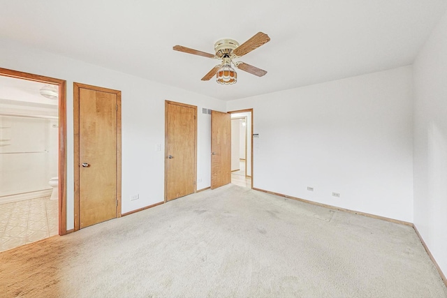 unfurnished bedroom with baseboards, ensuite bathroom, a ceiling fan, and light colored carpet