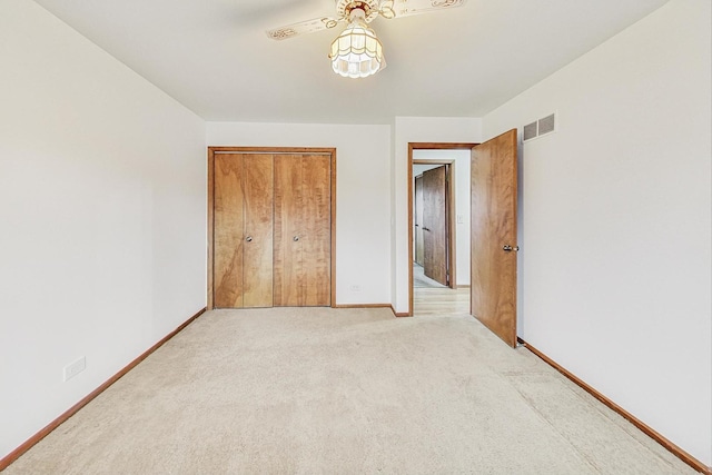 unfurnished bedroom with baseboards, visible vents, a closet, and light colored carpet