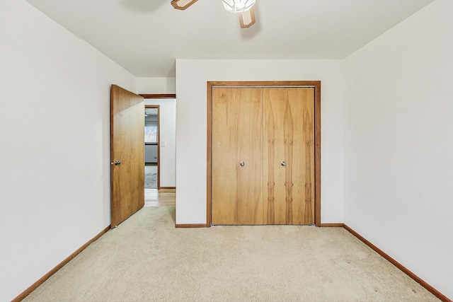 unfurnished bedroom with light carpet, a closet, a ceiling fan, and baseboards