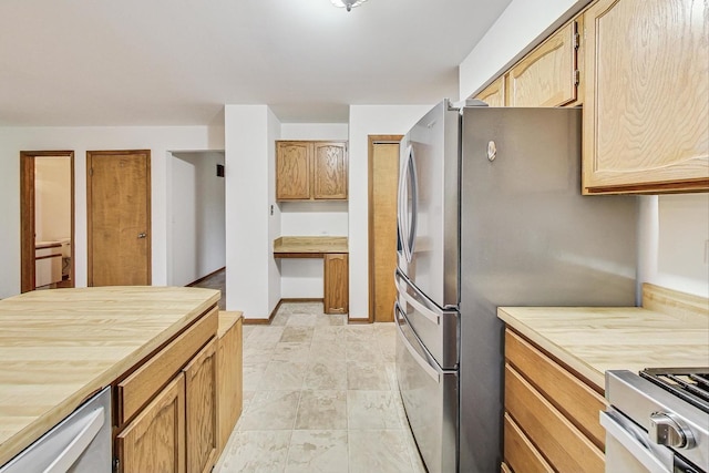 kitchen with butcher block counters, baseboards, range with gas stovetop, freestanding refrigerator, and dishwasher