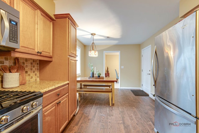 kitchen with dark wood-type flooring, stainless steel appliances, light stone counters, decorative light fixtures, and backsplash