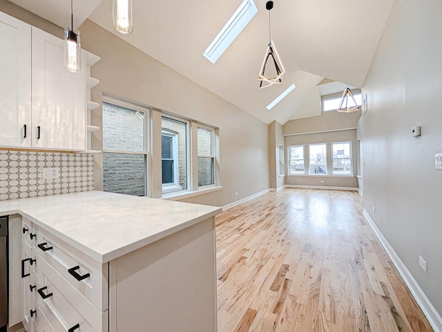 kitchen featuring white cabinetry, a skylight, light wood-type flooring, and decorative light fixtures