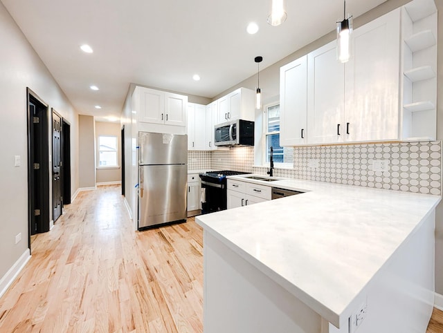 kitchen with appliances with stainless steel finishes, white cabinetry, hanging light fixtures, and kitchen peninsula