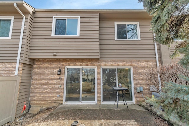 back of property with a patio area and brick siding