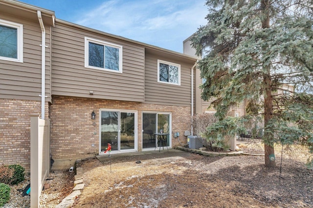 back of house featuring central AC unit and brick siding