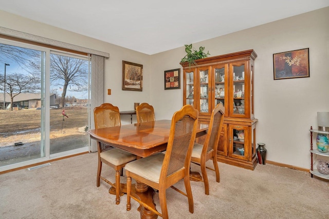 dining area featuring baseboards, visible vents, and light colored carpet