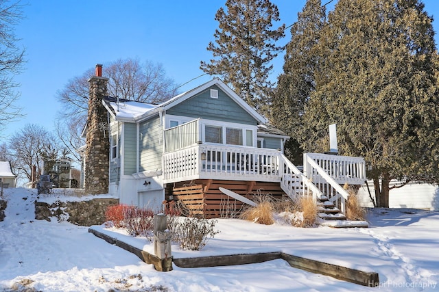 view of front of home featuring stairs, a chimney, and a wooden deck