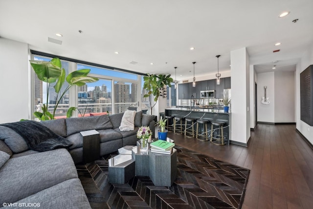 living room featuring baseboards, visible vents, dark wood-type flooring, a city view, and recessed lighting