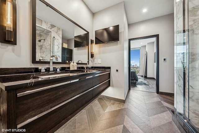 bathroom with ensuite bathroom, double vanity, a sink, and a marble finish shower