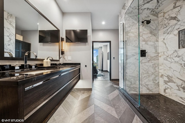 full bath featuring double vanity, a sink, and a marble finish shower