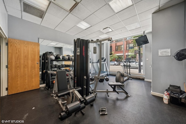 gym with a paneled ceiling, visible vents, and baseboards