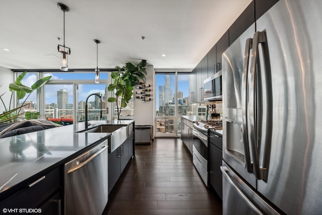 kitchen featuring appliances with stainless steel finishes, a view of city, pendant lighting, and dark cabinetry