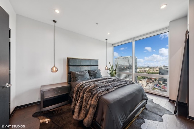 bedroom featuring floor to ceiling windows, a city view, recessed lighting, wood finished floors, and baseboards