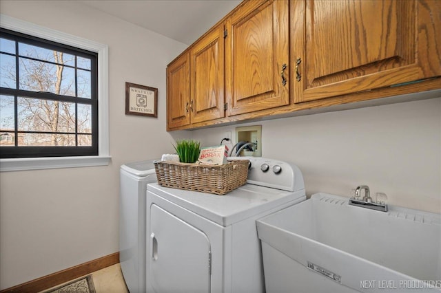 washroom featuring a sink, washing machine and clothes dryer, cabinet space, and baseboards