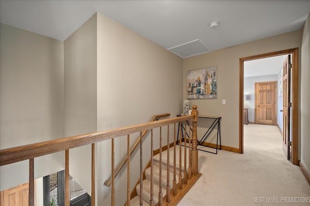 hall with attic access, baseboards, light colored carpet, and an upstairs landing