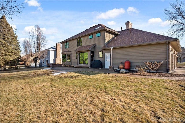 back of house featuring a yard, a chimney, and roof with shingles