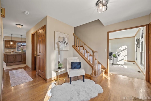 foyer with light wood-style flooring, baseboards, and stairs