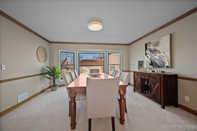 dining area with light colored carpet, visible vents, crown molding, and baseboards