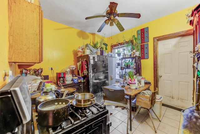 kitchen with light tile patterned floors, ceiling fan, and black fridge