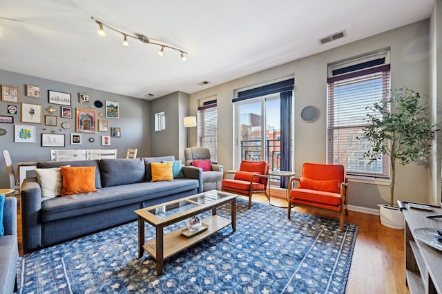 living area featuring baseboards, track lighting, visible vents, and wood finished floors